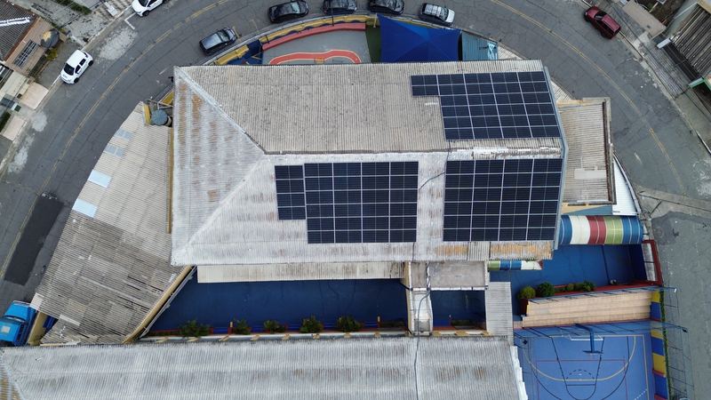 Vista aérea de módulos solares em cobertura de instituição de ensino — instalação da E5 Solar Energia