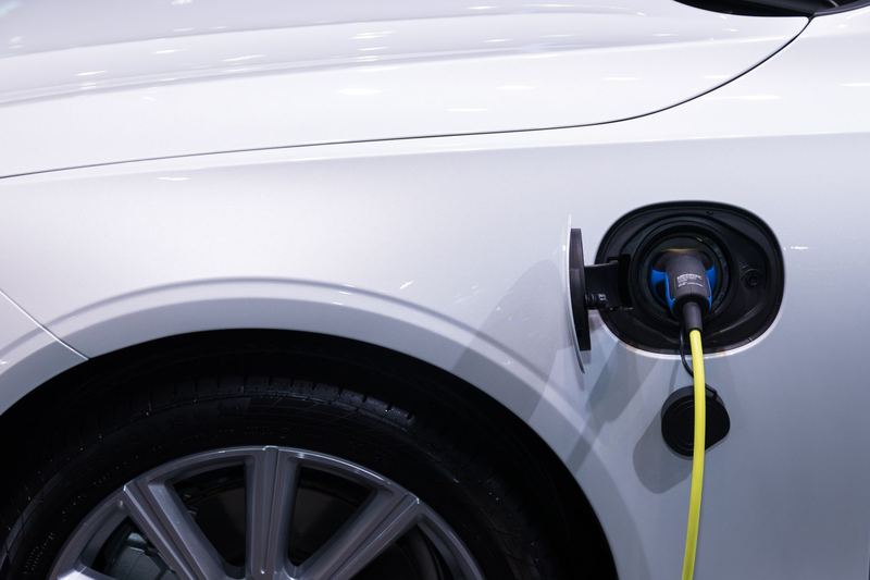 Carro elétrico branco com plugue de recarga conectado — imagem ilustrativa de banco